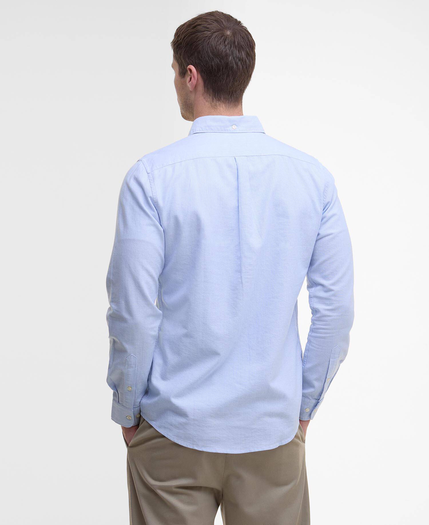 Man wearing a light blue shirt and beige pants on a white background