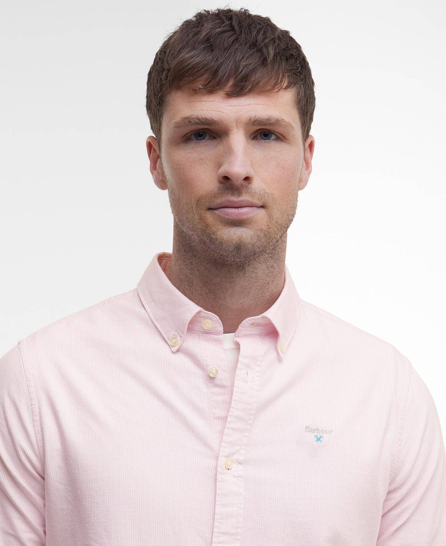 Man wearing a light pink Barbour shirt against a plain background