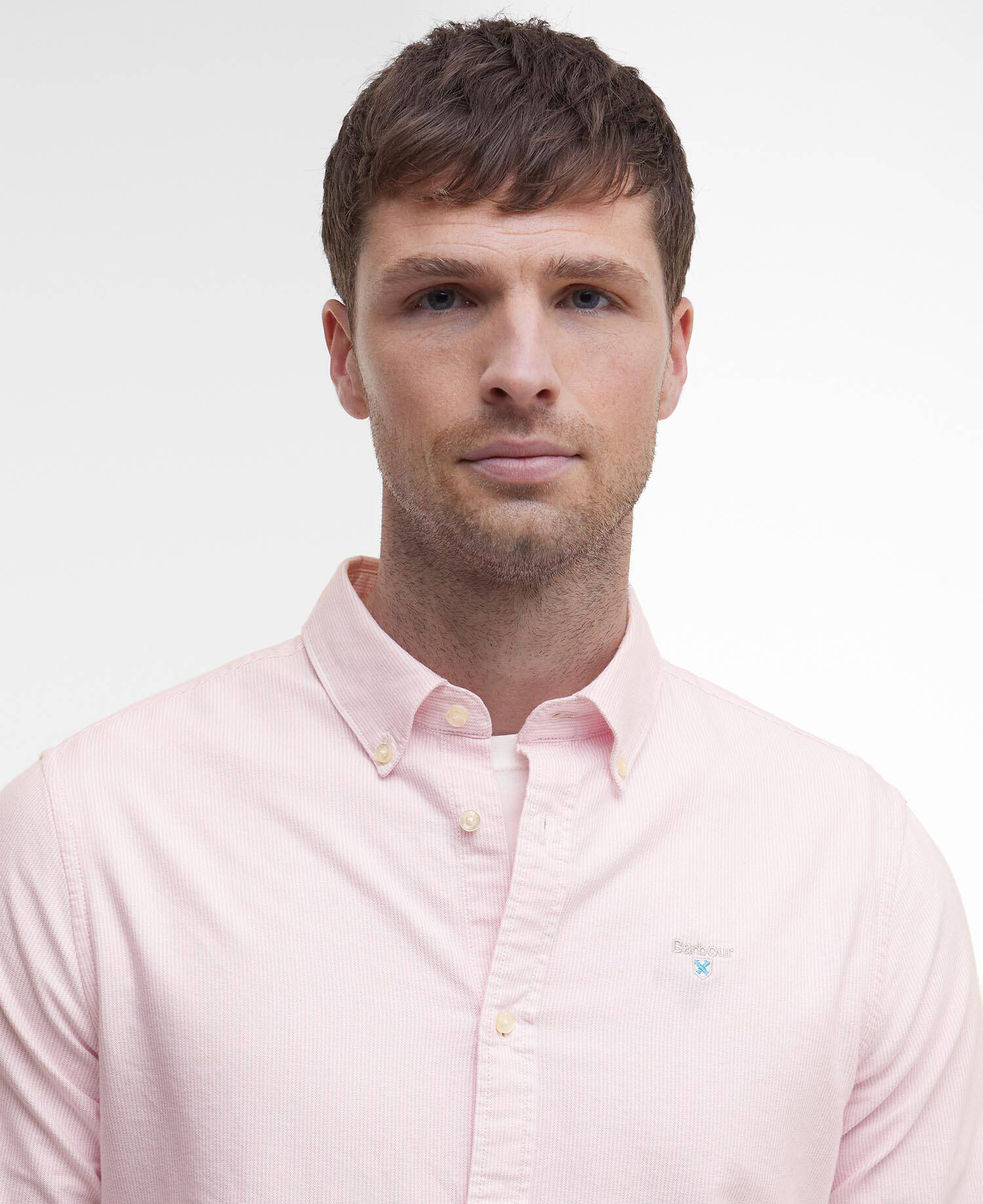 Man wearing a light pink Barbour shirt against a plain background