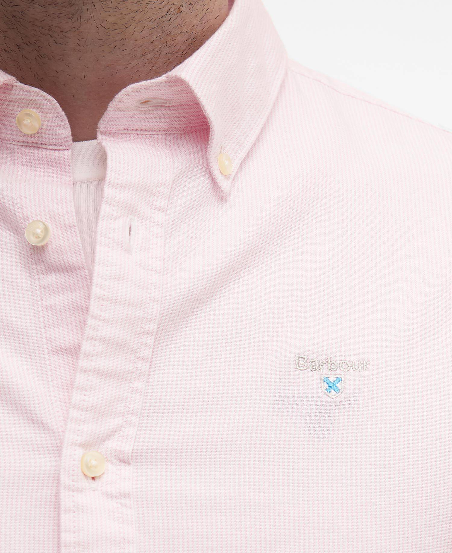 Close-up of a pink striped shirt with a Barbour brand logo on a white background