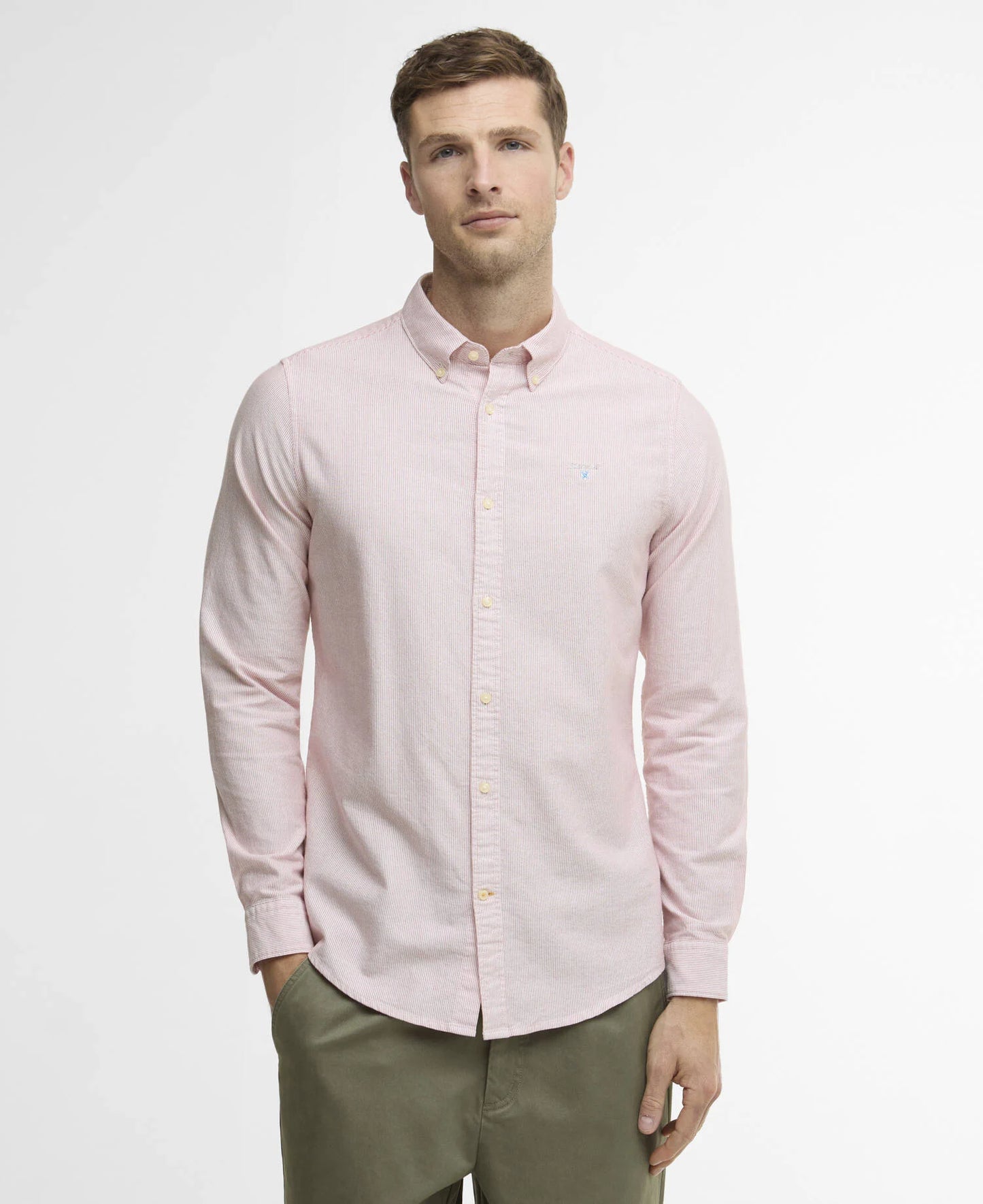 Man wearing a light red shirt and green pants against a white background