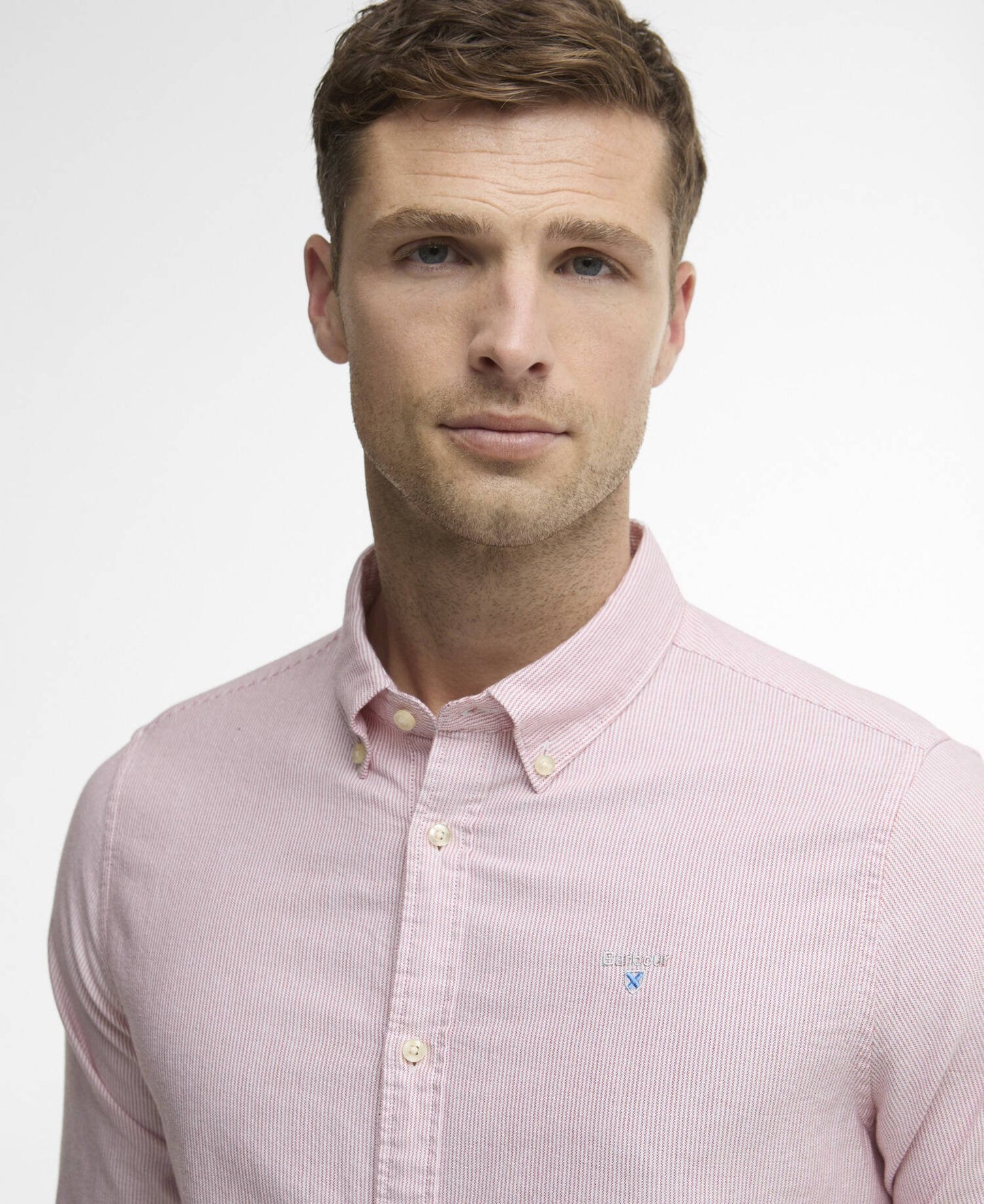 Man wearing a subtle red striped shirt with a Barbour logo against a white background