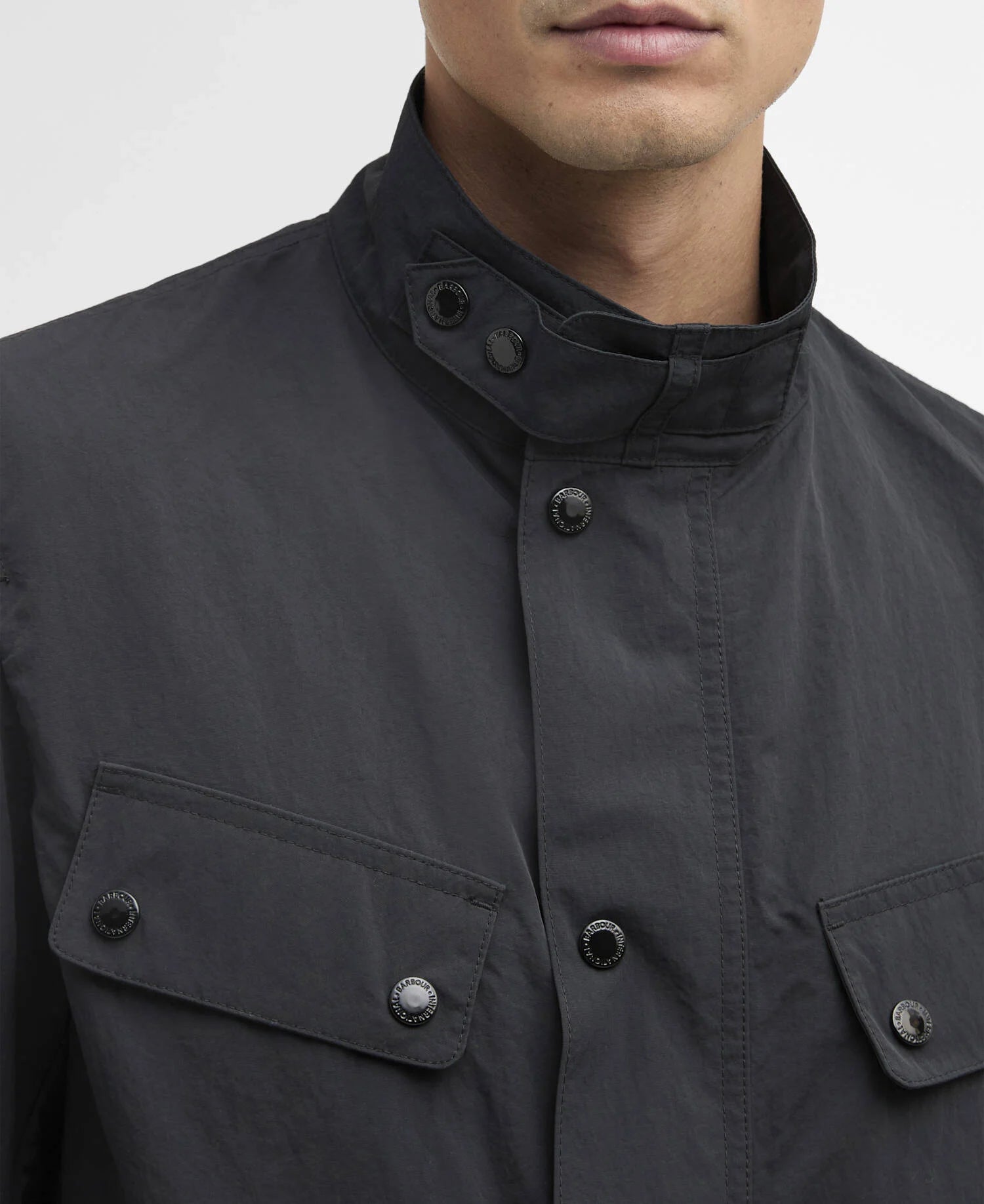 Close-up of a black jacket with button details on a plain background