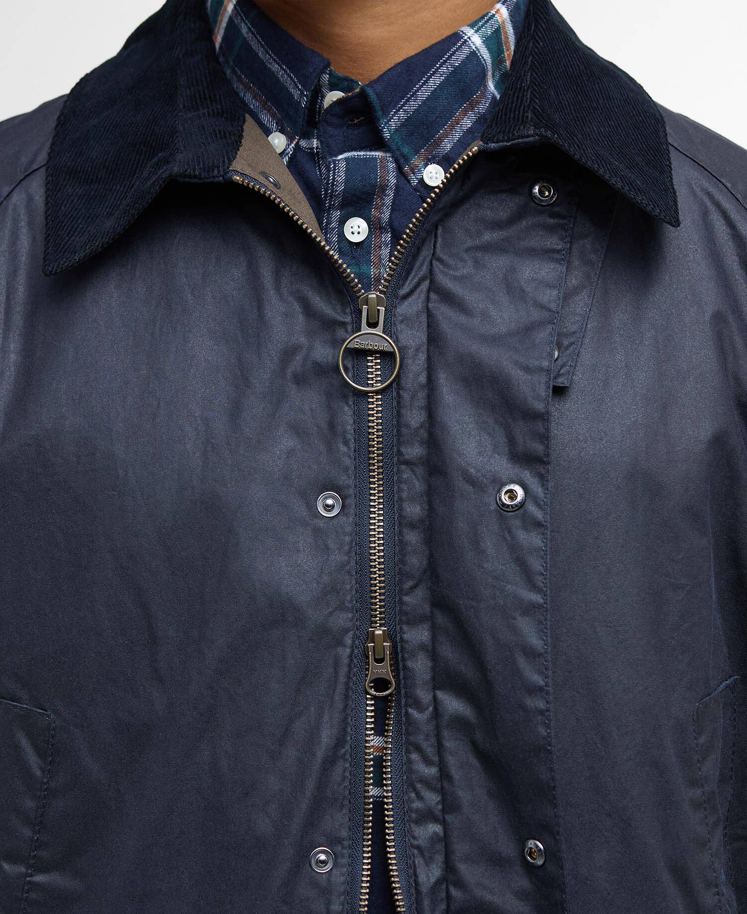 Navy jacket with a plaid shirt underneath on a neutral background