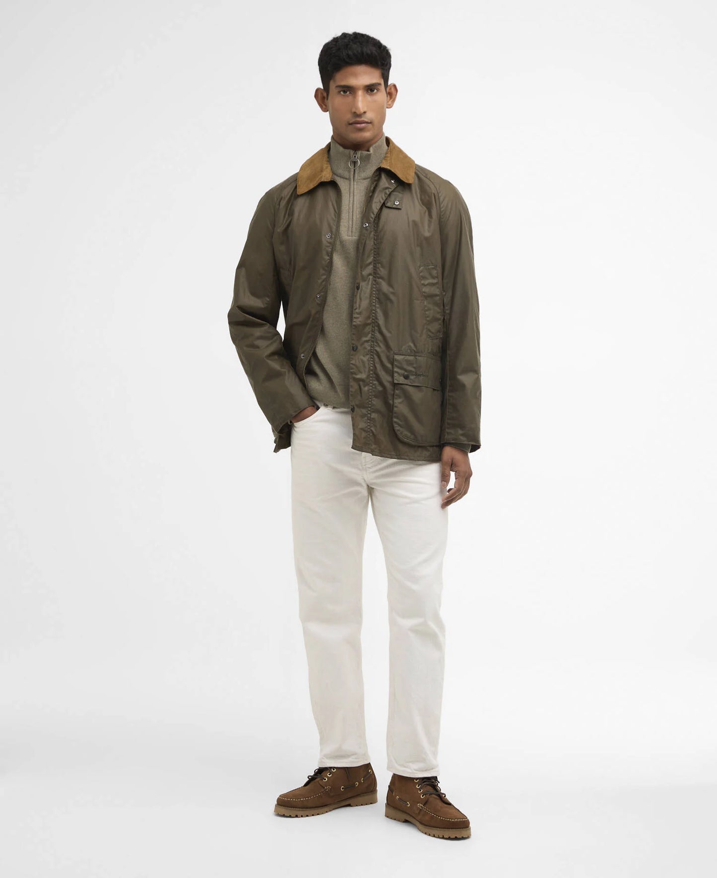 Man wearing a green jacket with a brown collar, white pants, and brown boots on a white background