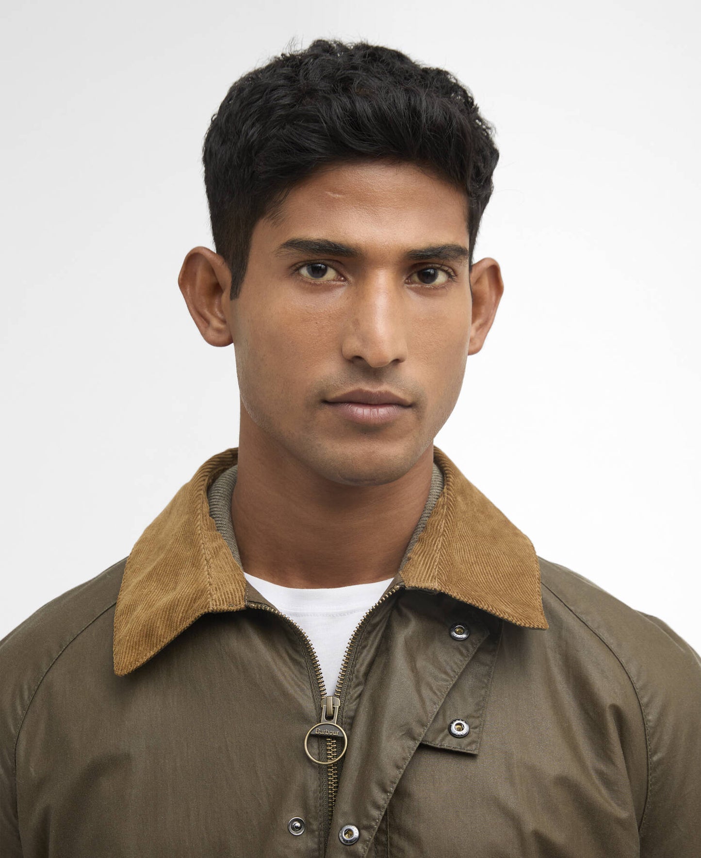Man wearing a olive green jacket with a tan collar against a white background