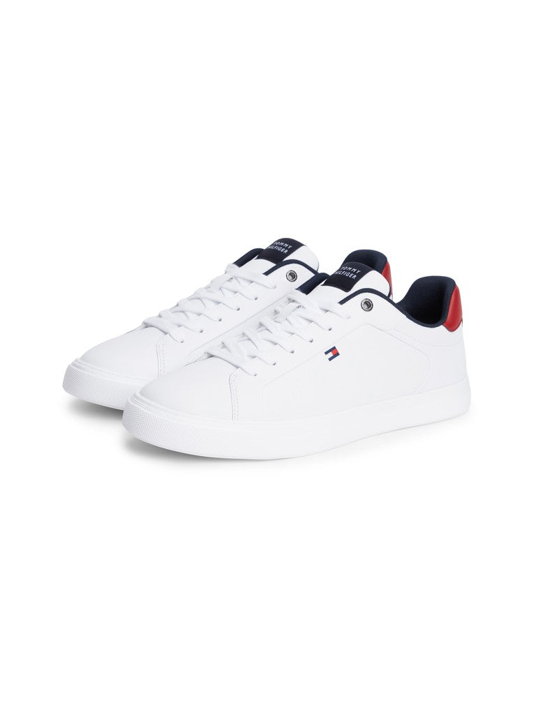 A pair of white low-top sneakers with navy blue and red accents, featuring the Tommy Hilfiger flag logo on the side and tongue.