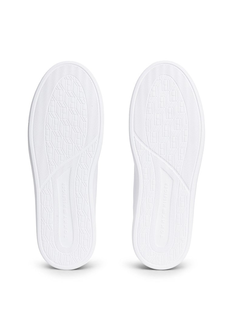 A pair of white athletic sneakers shown from the sole view, displaying the textured tread patterns on a clean white background.