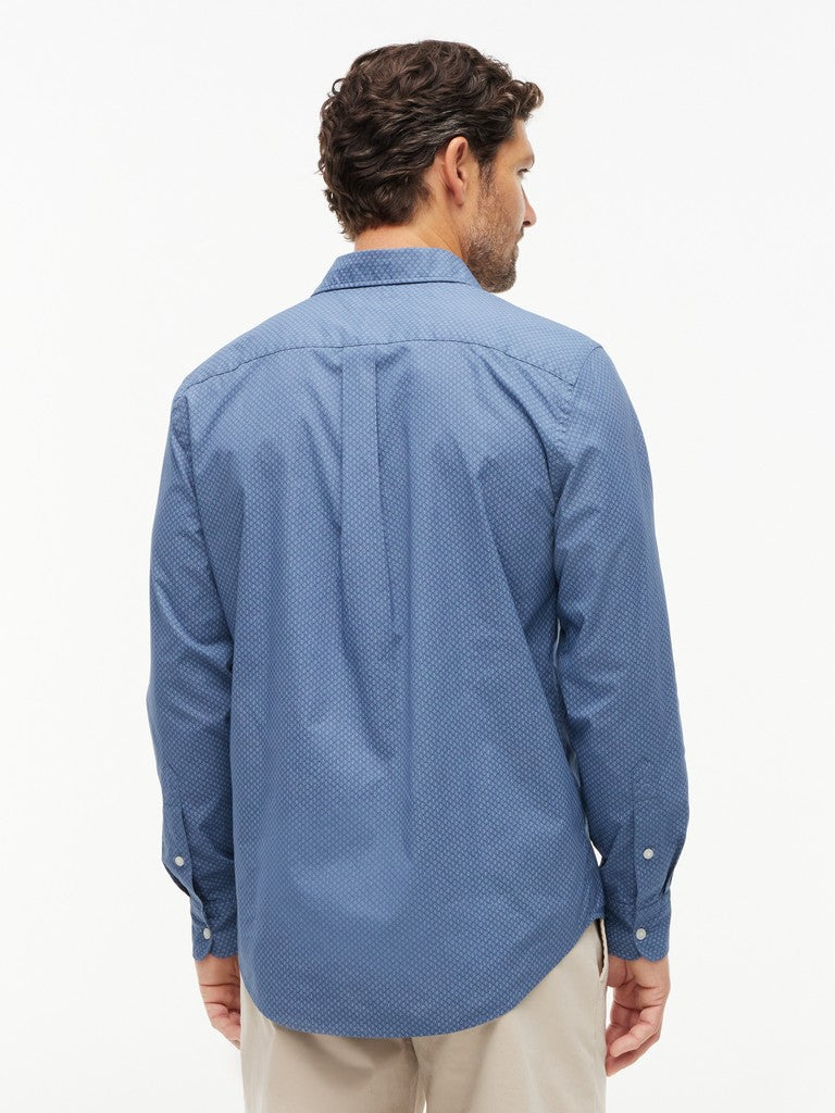 A man viewed from the back wearing a blue micro-patterned long-sleeve button-down shirt and beige trousers, set against a plain white studio background.
