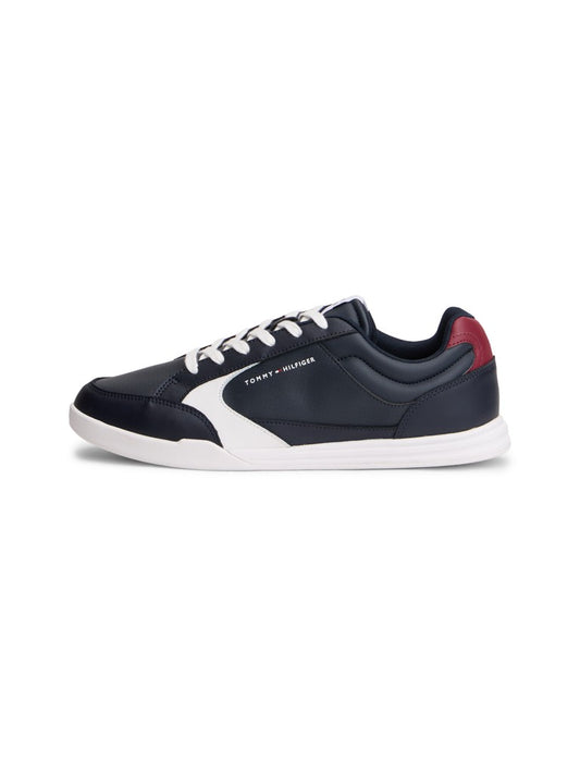 Navy athletic shoe from the side featuring the Tommy Hilfiger logo and white and red accents with white laces