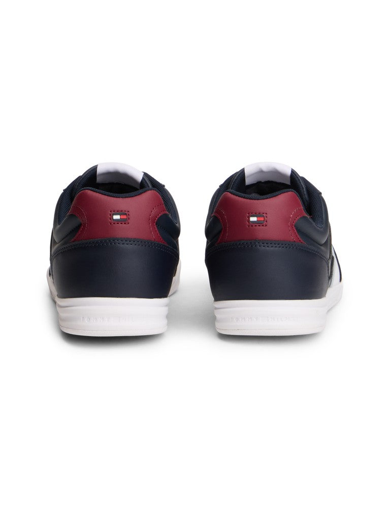 A pair of Tommy Hilfiger low-top sneakers shown from the back, featuring navy blue leather uppers, burgundy heel panels, and white soles.