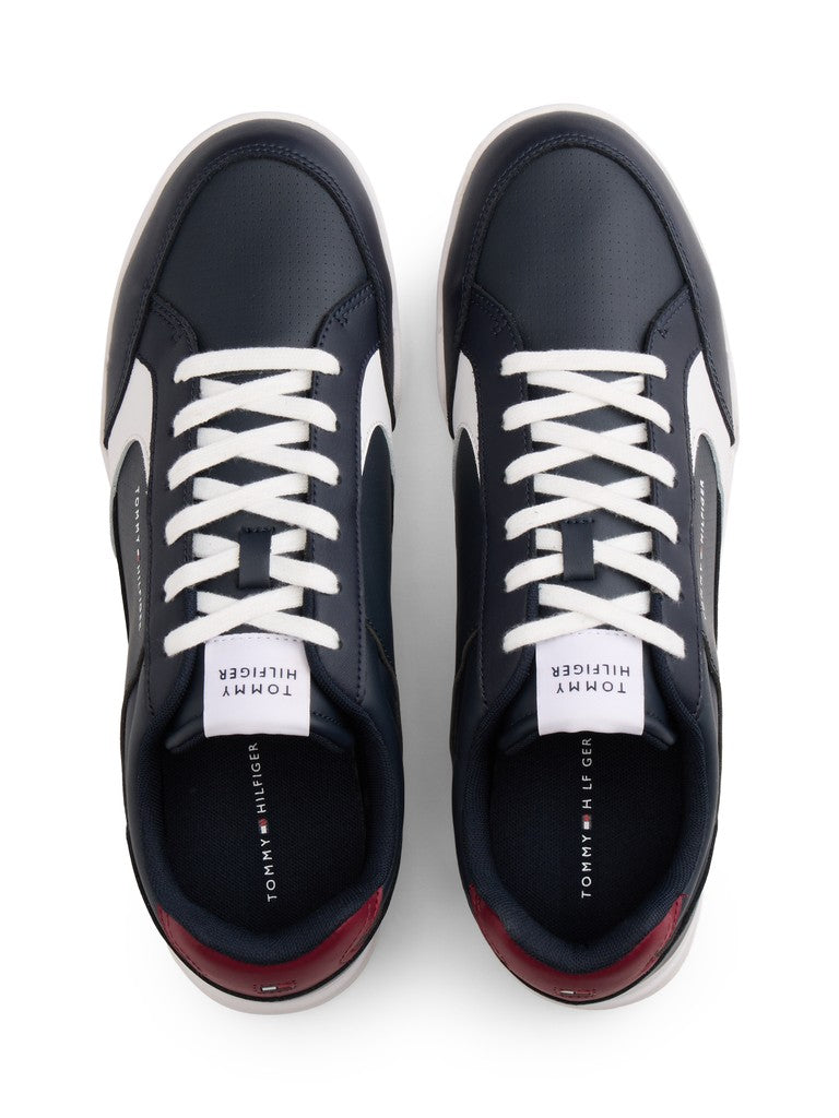 A pair of Tommy Hilfiger low-top sneakers shown from a top-down view. The sneakers are navy blue with white laces, white side stripes, and a dark red heel accent.