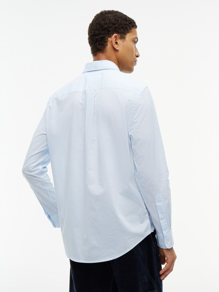 A man wearing a light blue long-sleeve button-down shirt, shown from the back against a plain white studio background.