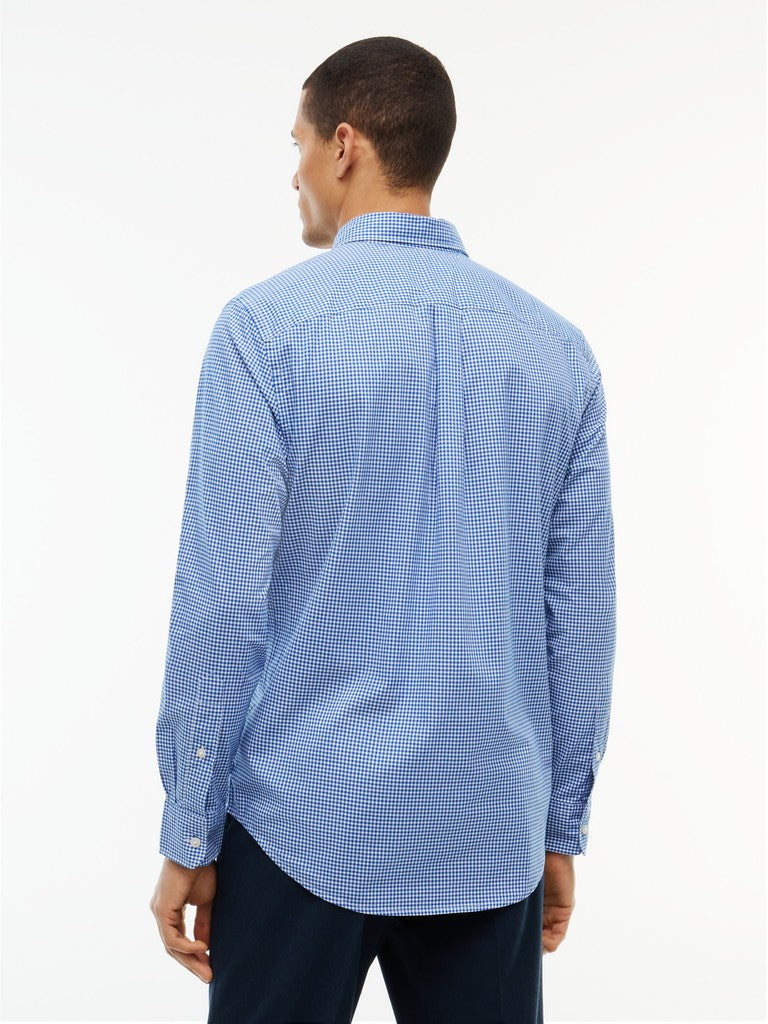 A man viewed from the back wearing a light blue and white micro-checkered long-sleeve button-down shirt and dark trousers, set against a plain white studio background.