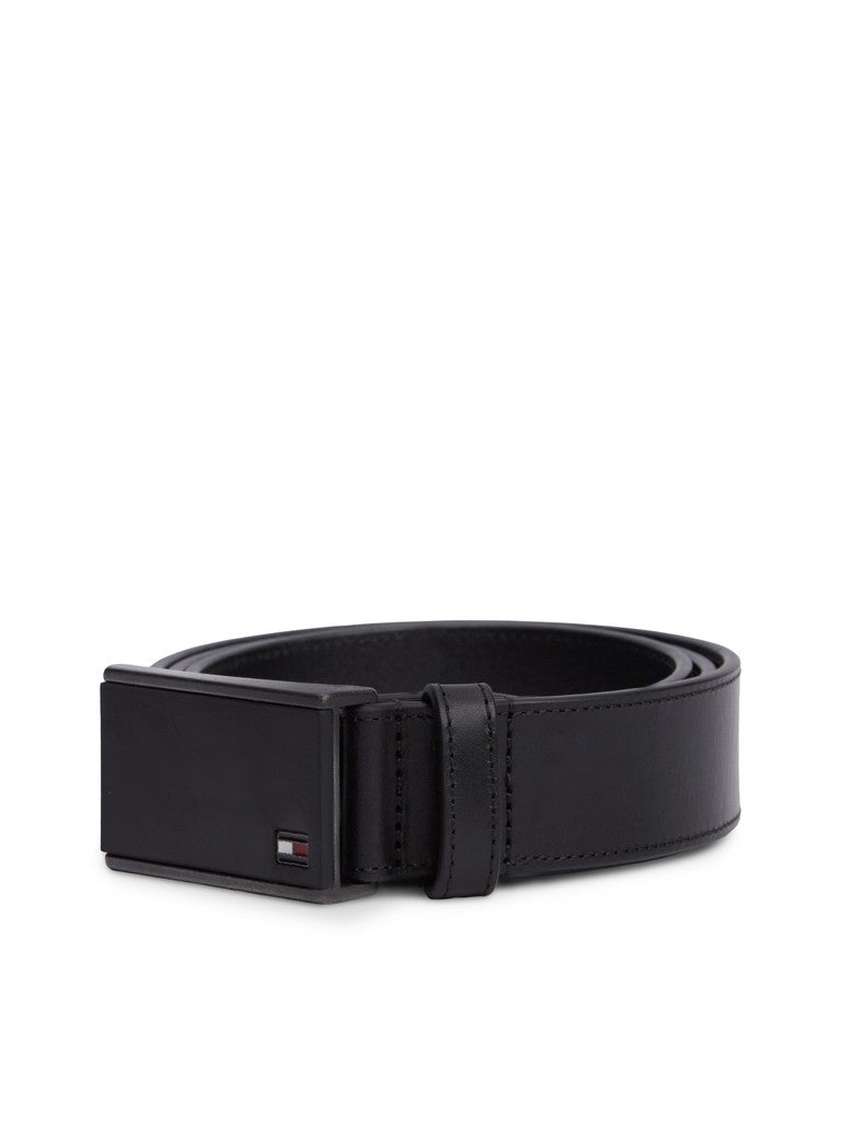 Black leather belt curled in a circle with a black metallic plaque buckle with small Tommy Hilfiger flag logo in the bottom corner