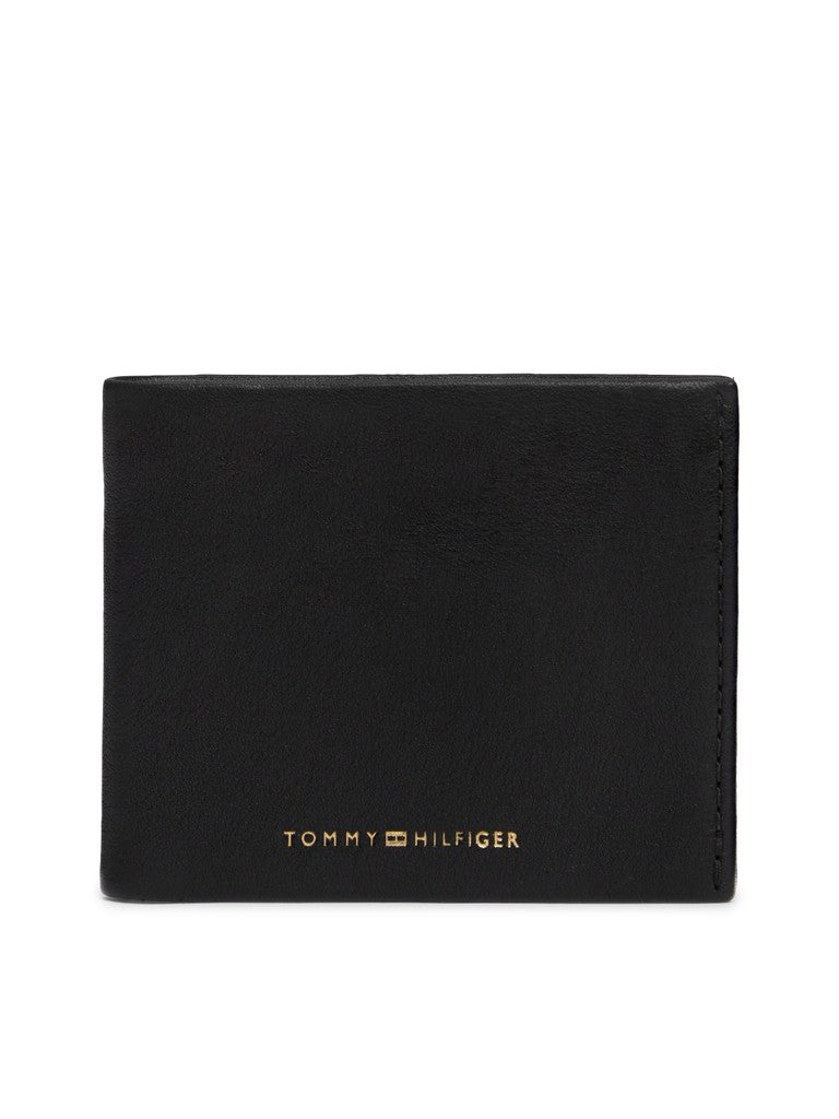 A black leather bifold wallet with gold-toned 'TOMMY HILFIGER' branding on the front, shown against a plain white background.