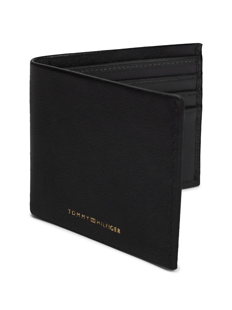 A black Tommy Hilfiger bifold wallet with gold lettering, shown partially open on a white background.