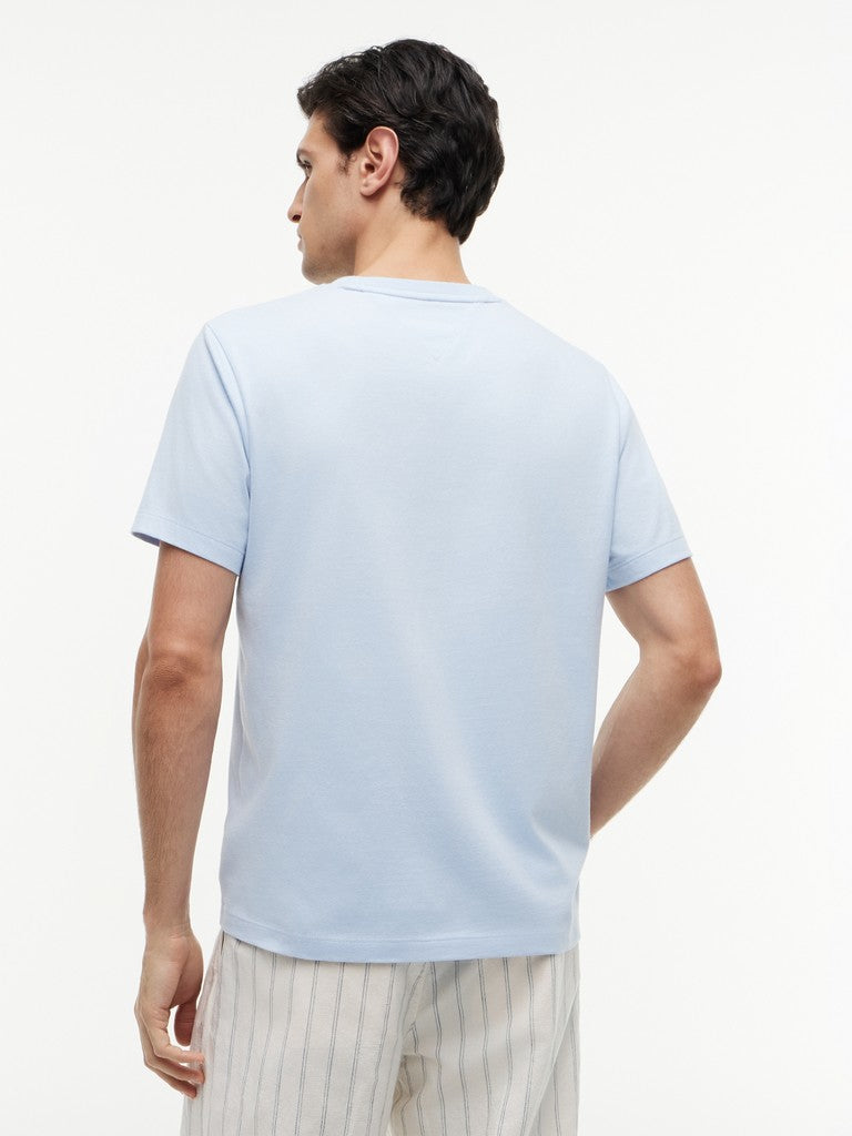 Man wearing a light blue t-shirt and white pants on a plain background