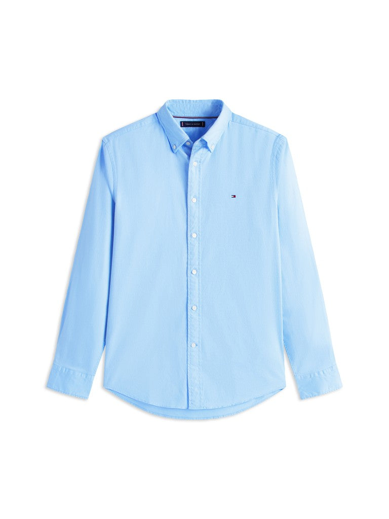 A light blue long-sleeve button-down shirt with a small embroidered Tommy Hilfiger flag logo on the left chest, displayed on a clean white background.