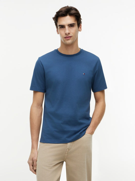Man wearing a blue t-shirt with a Tommy Hilfiger brand logo on a white background