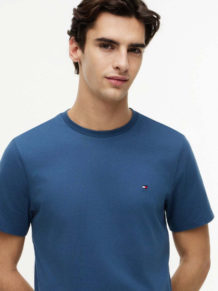 Man wearing a blue t-shirt with a small Tommy Hilfiger logo on a white background
