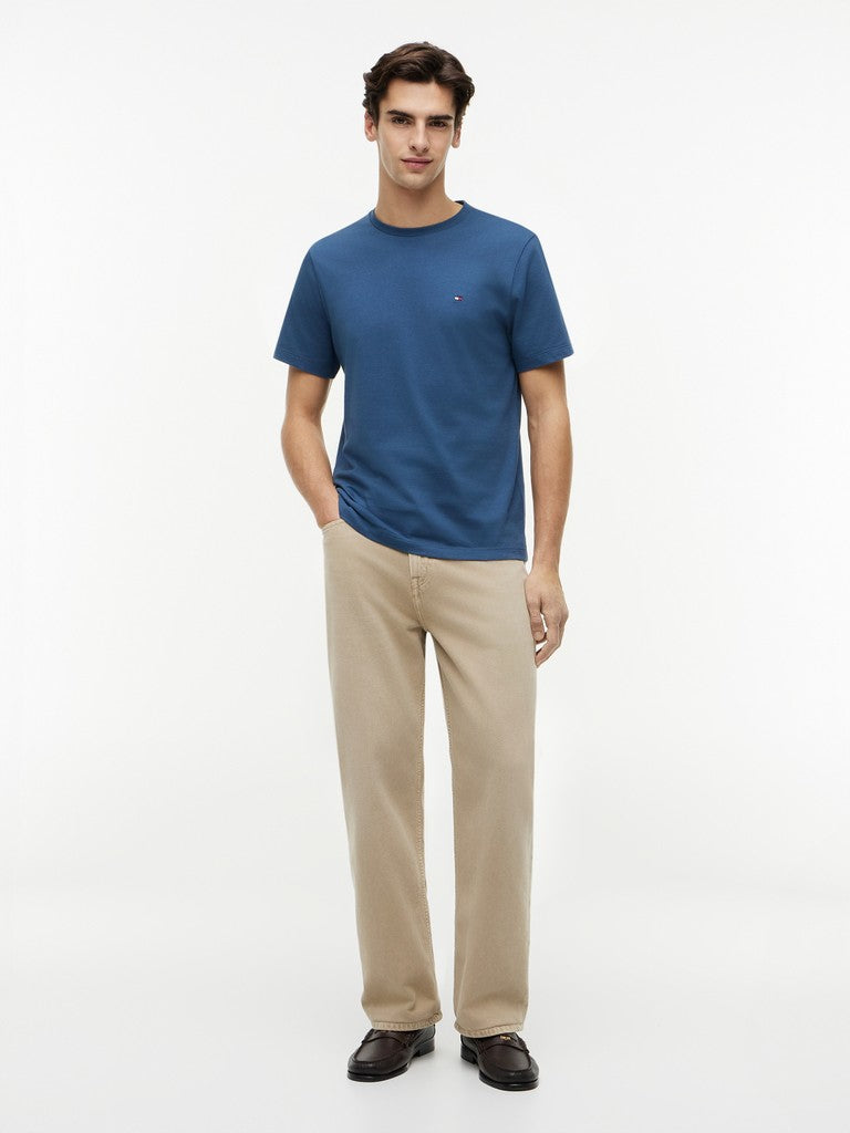Man wearing a blue t-shirt and beige pants on a white background