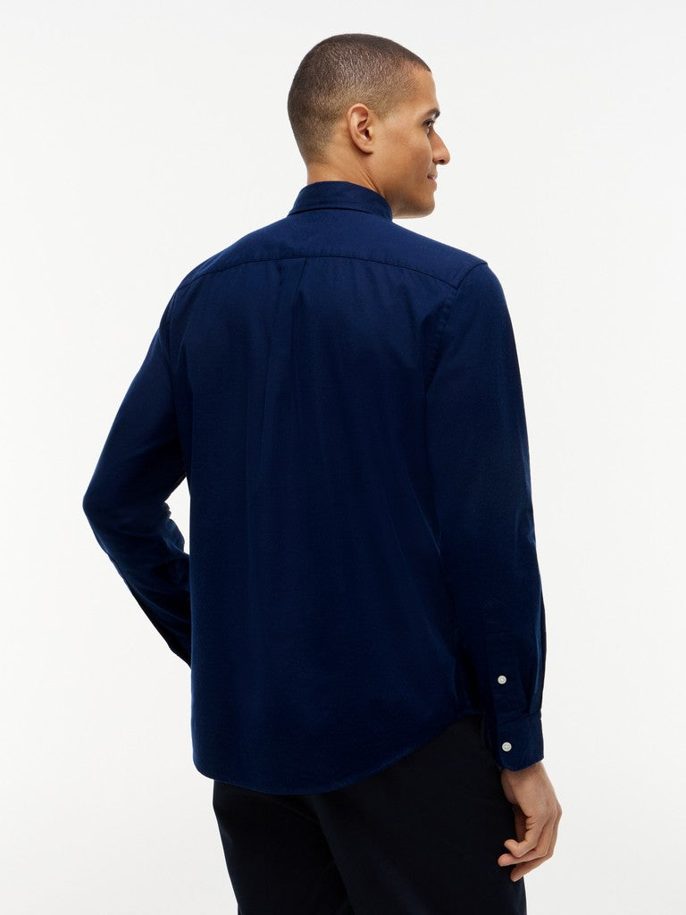 A man wearing a navy blue long-sleeve button-down shirt, shown from a three-quarters back view against a plain white studio background.