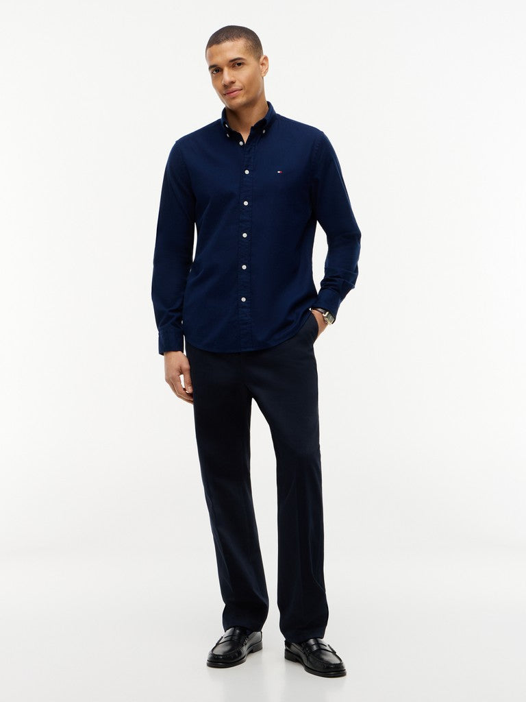 A man modeling a dark navy blue long-sleeve button-down shirt with matching navy trousers and black dress shoes, standing against a plain white studio background.