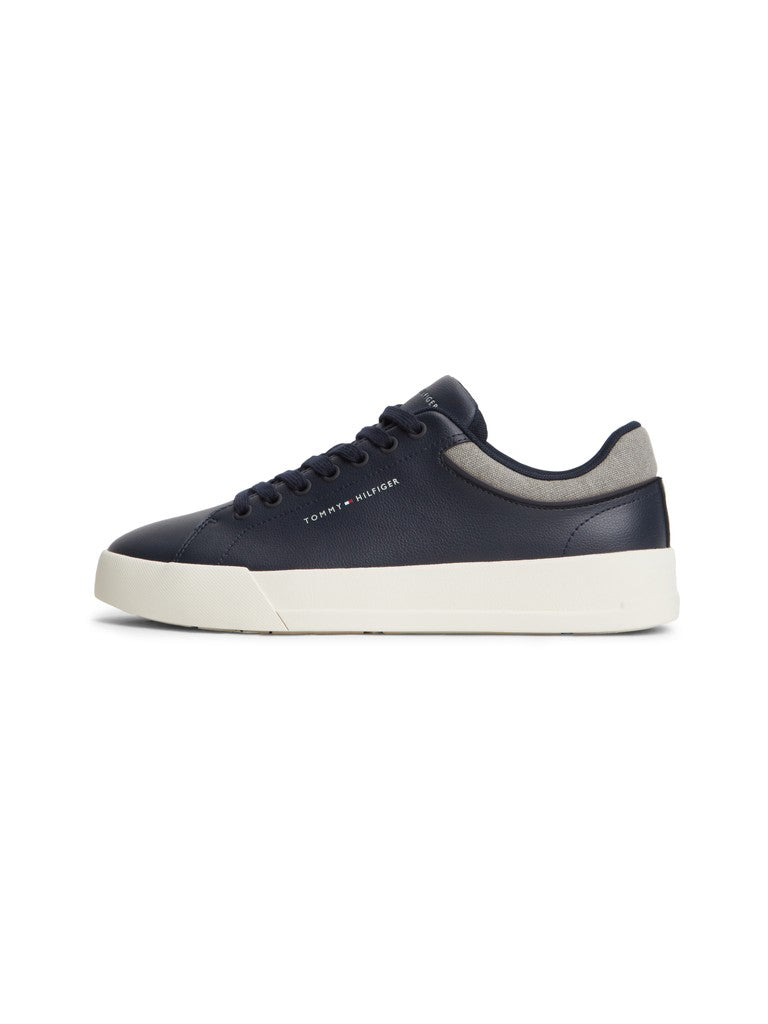 A low-top sneaker by Tommy Hilfiger in navy blue leather with a thick white platform sole and a light gray heel tab, shown in a side profile on a white background.