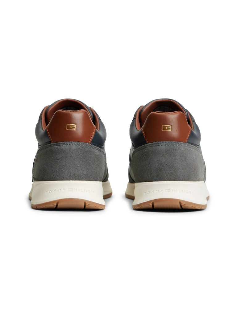 Pair of Tommy Hilfiger leather suede lace up sneakers heel view with Tommy Hilfiger flag logo in gold. Navy and grey panes with brown details