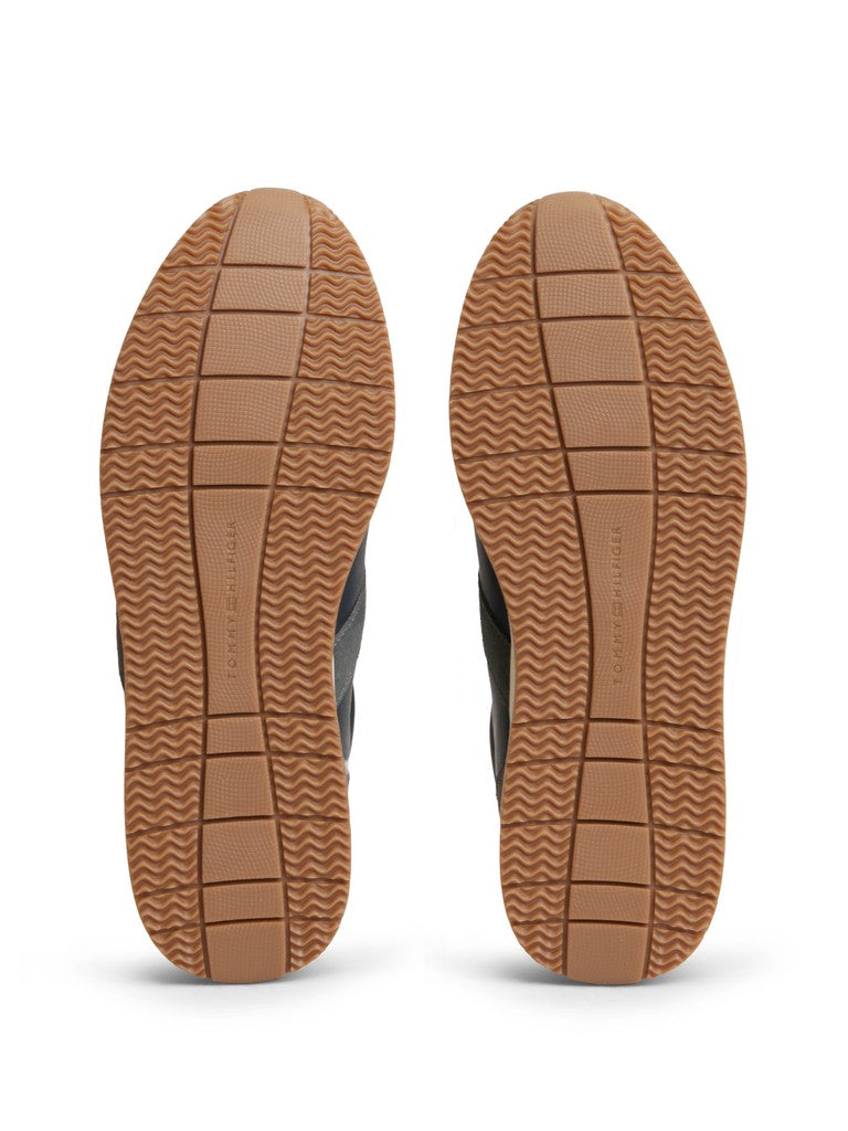 Out sole of a pair of Tommy Hilfiger sneakers with a light brown colour and wavy tread pattern grips and Tommy Hilfiger logo