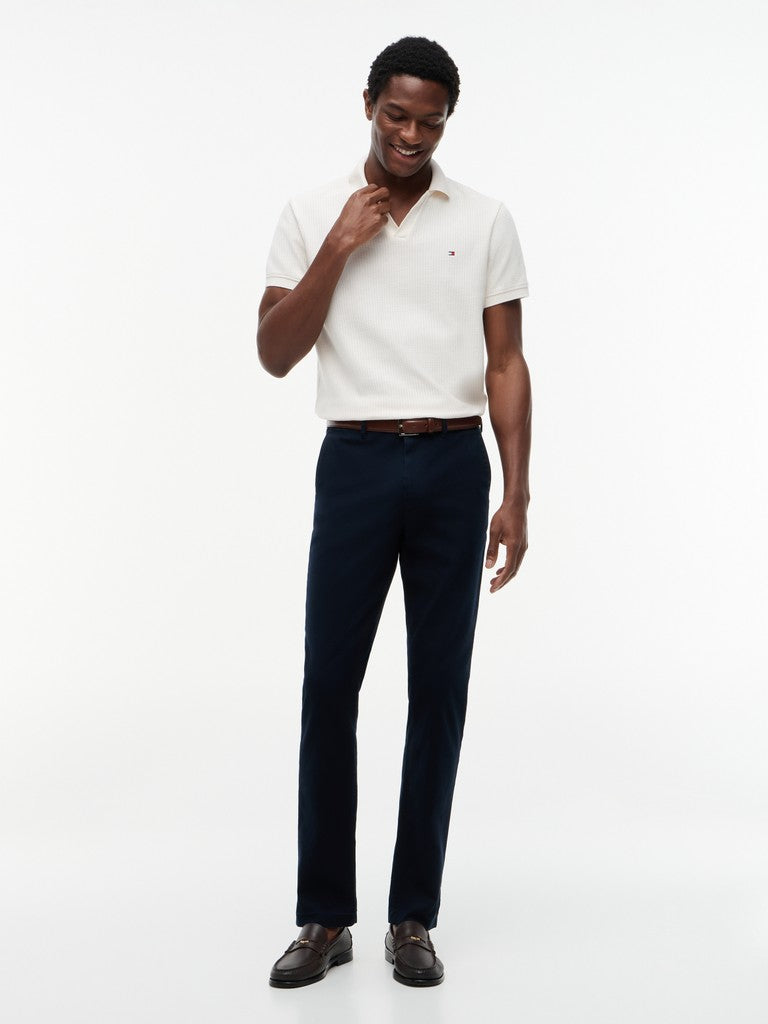 Man wearing a white polo shirt and navy pants on a white background