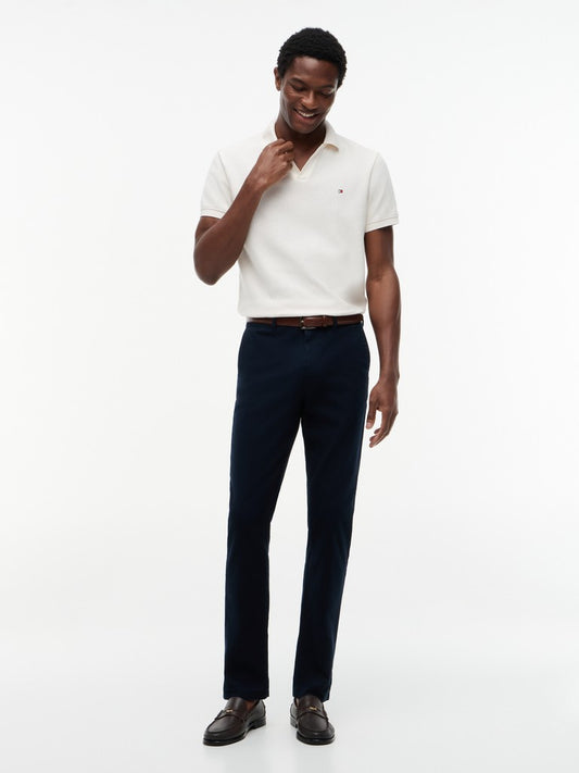 Man wearing a white polo shirt and navy pants on a white background