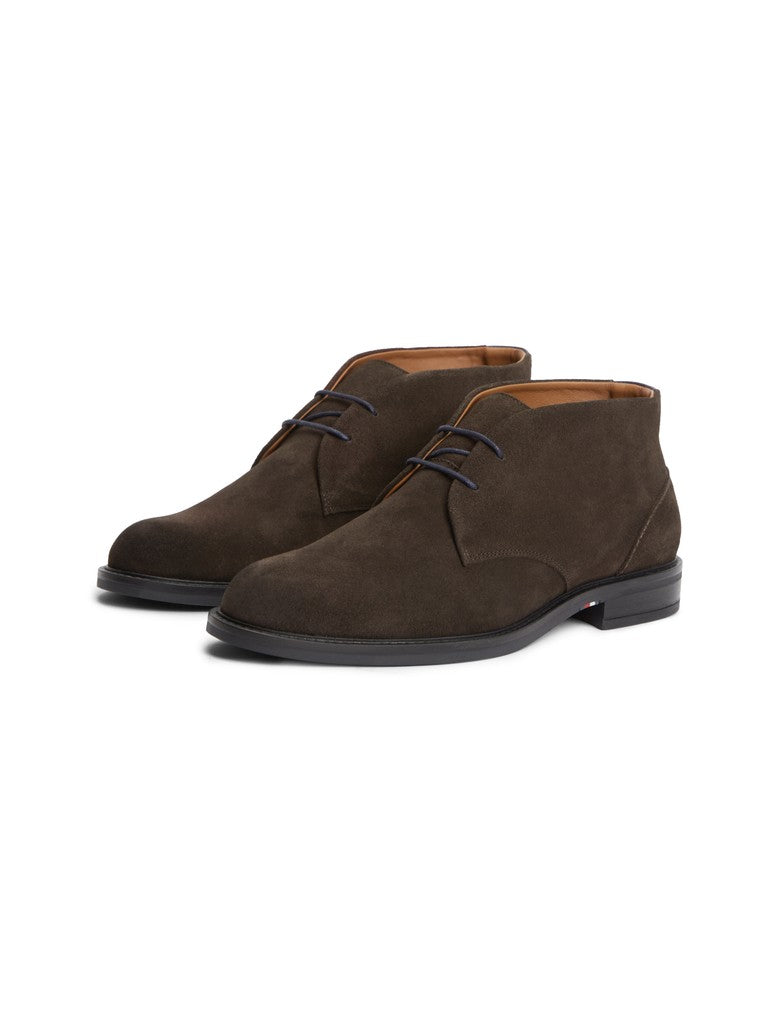 A pair of dark brown suede chukka boots with black soles and navy laces, displayed on a clean white background.