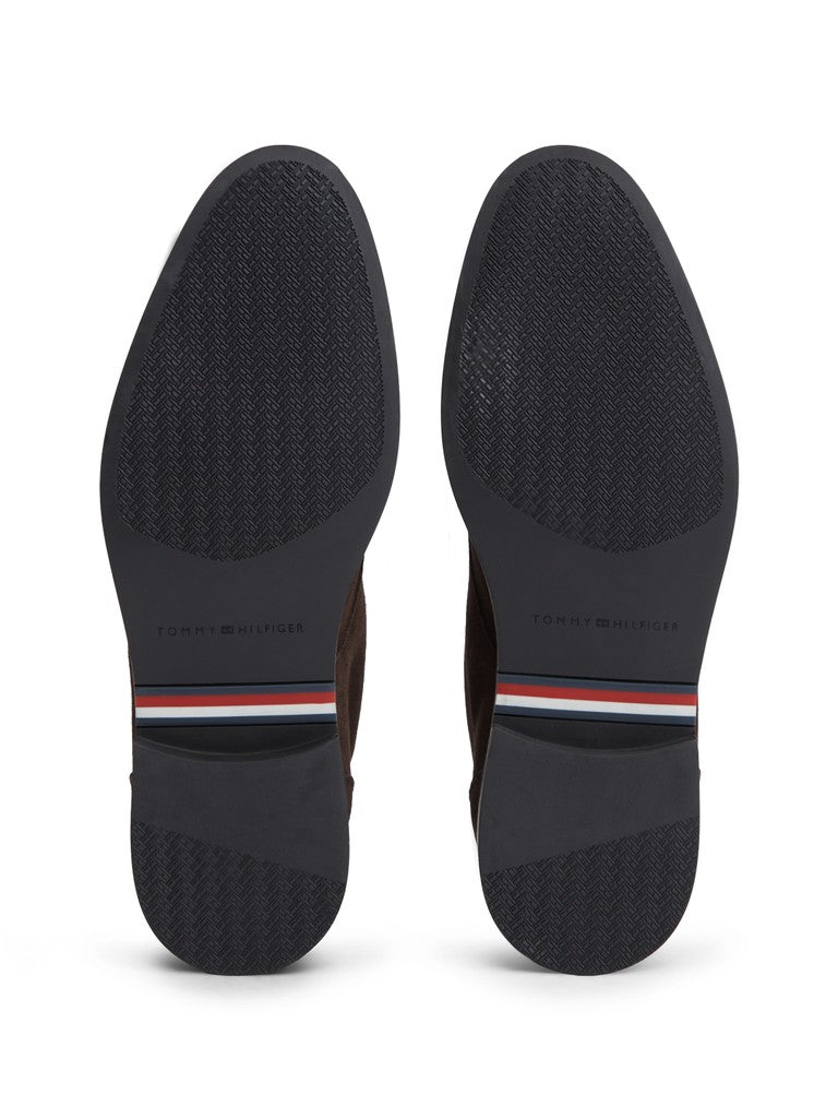 Sole view of a pair of black shoes showing the textured outsoles, featuring Tommy Hilfiger logo and signature red, white, and blue stripe detail on the heel.