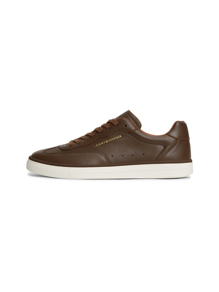 Brown and white sneaker with a gold Tommy Hilfiger logo on the side on a white background
