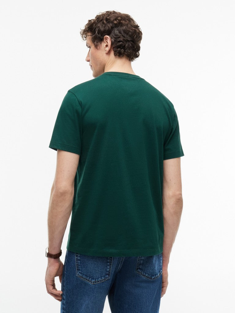 A man viewed from the back wearing a dark green short-sleeve crewneck t-shirt and blue jeans against a plain white background.