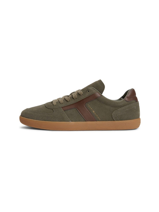 A low-top suede sneaker featuring a brown leather "T" pattern with gold Tommy Hilfiger logo on the side and a gum sole shown on a light gray background.