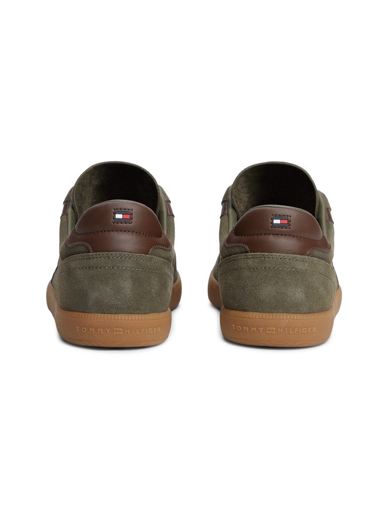 A pair of Tommy Hilfiger low-top sneakers shown from the back, featuring olive green suede and brown leather panels with a brown gum sole.