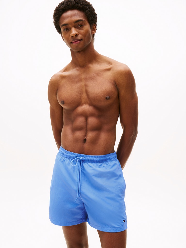 Man wearing blue swim shorts on a white background
