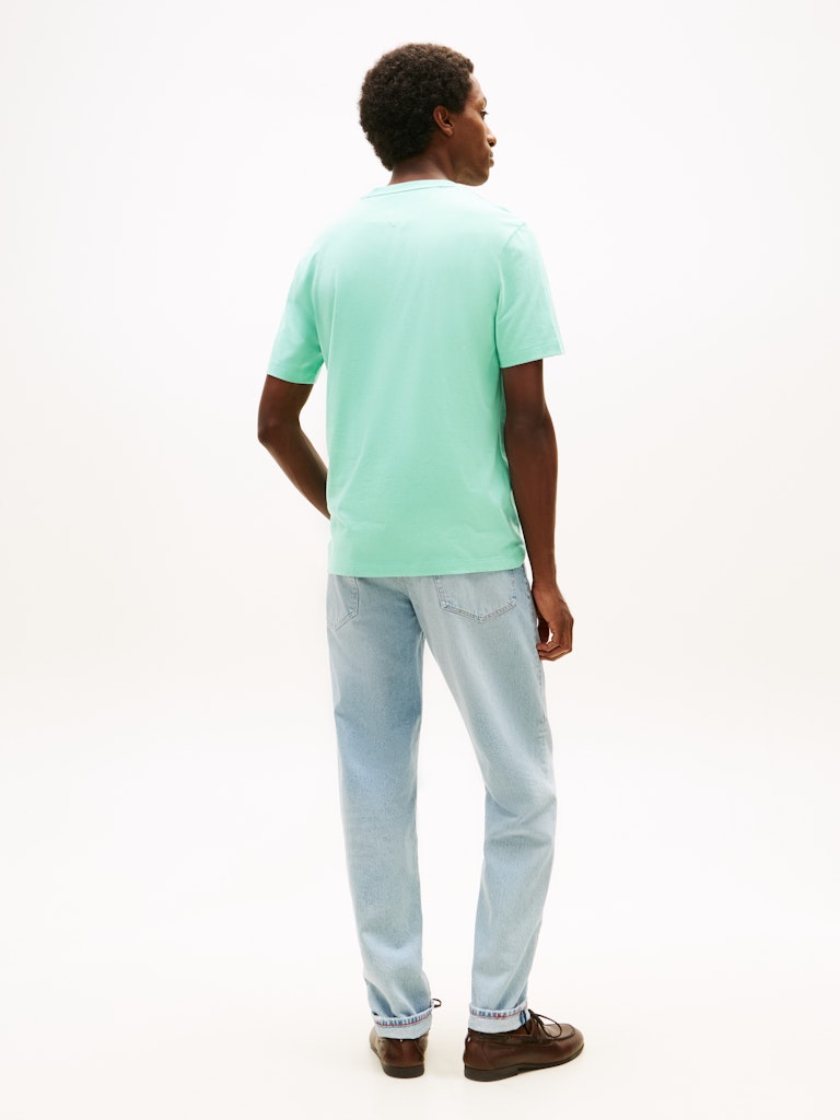 Person wearing a light green t-shirt and light blue jeans on a white background
