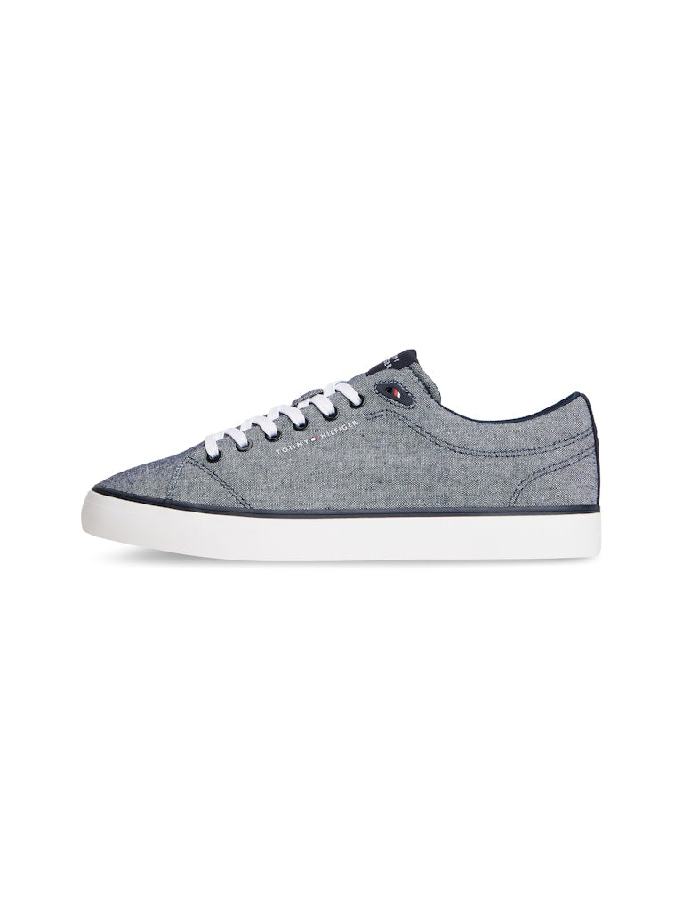 Side view of a canvas lace up casual shoe in a blue grey colour with white sole and a Tommy Hilfiger logo on the side