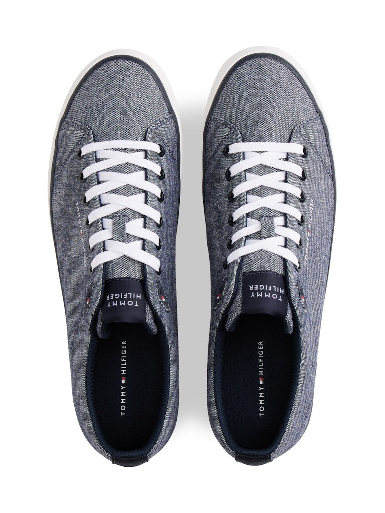 Top down view of canvas lace up casual shoes in a blue grey colour with white sole and Tommy Hilfiger logos through out