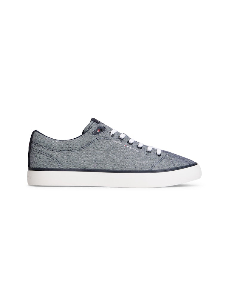 Side view of a canvas lace up casual shoe in a blue grey colour with white sole and a Tommy Hilfiger logo on the side