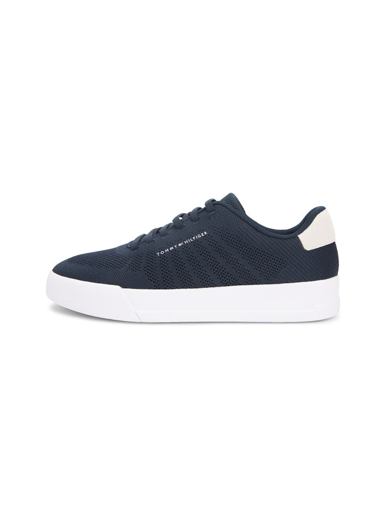 Side view of a dark blue sneaker with white sole unit. Tommy Hilfiger logo on the side