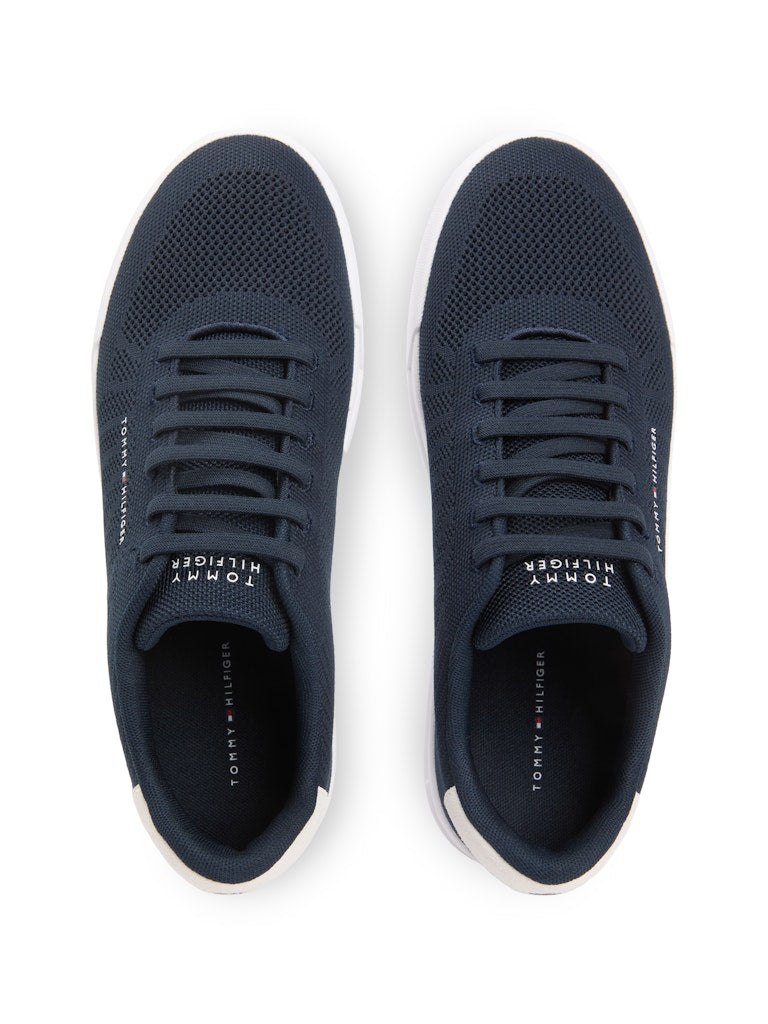 Top down view of dark blue sneakers with white sole unit. Tommy Hilfiger logo in various places