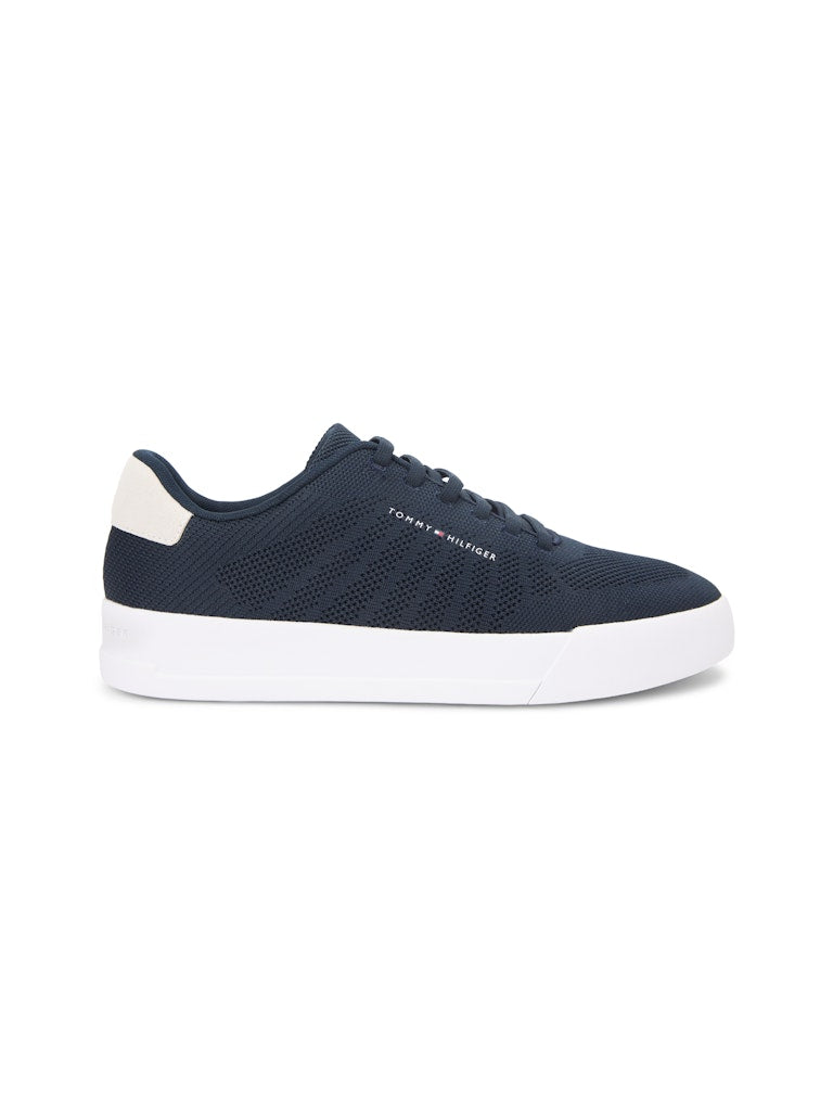 Side view of a dark blue sneaker with white sole unit. Tommy Hilfiger logo on the side