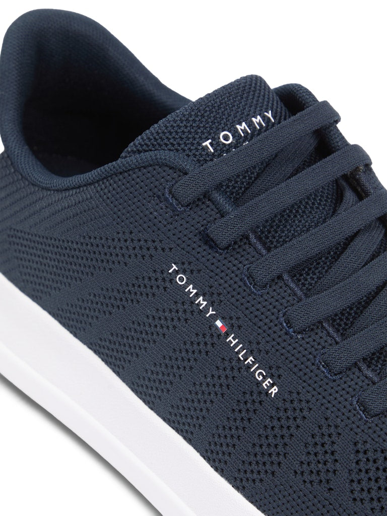 Close up of a dark blue mesh sneaker with laces and white sole unit. Tommy Hilfiger logo on the side