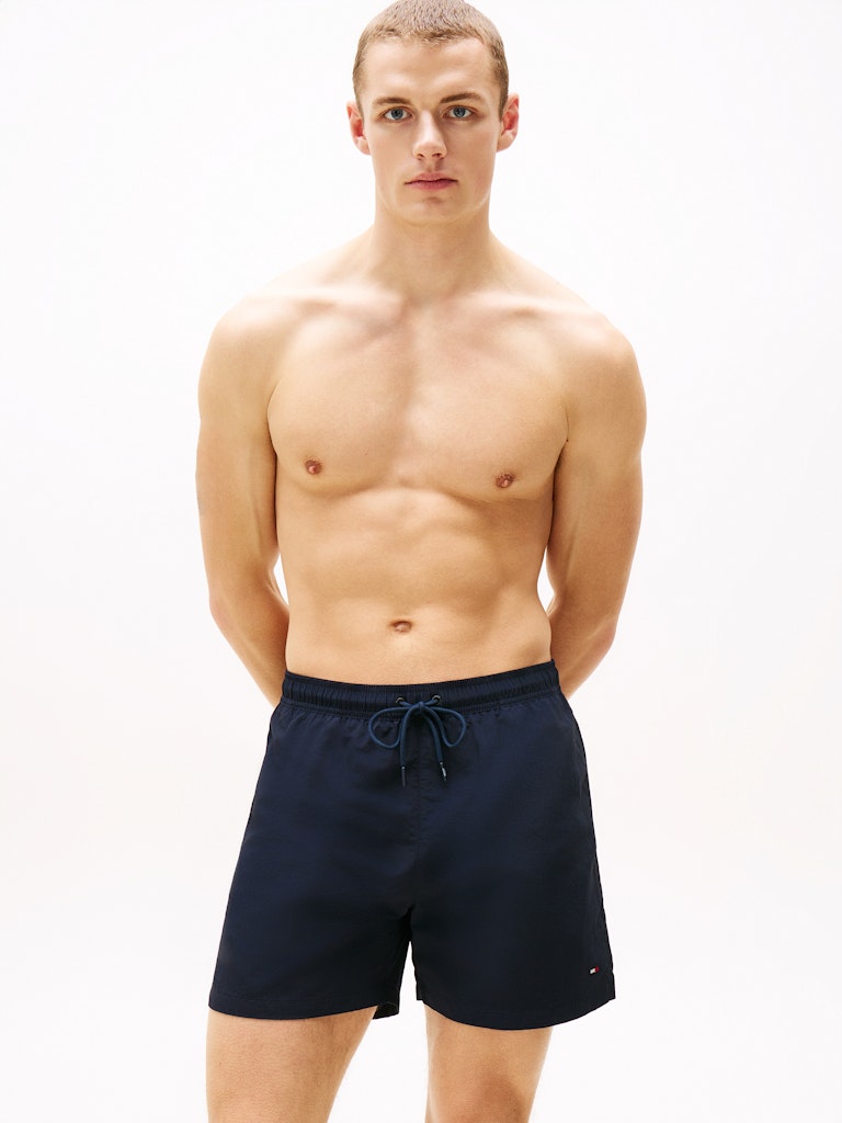Man wearing navy swim shorts on a plain background