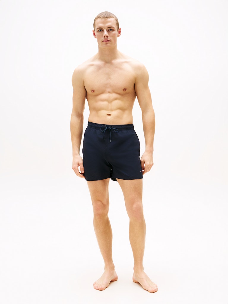 Man wearing navy blue swim shorts on a white background